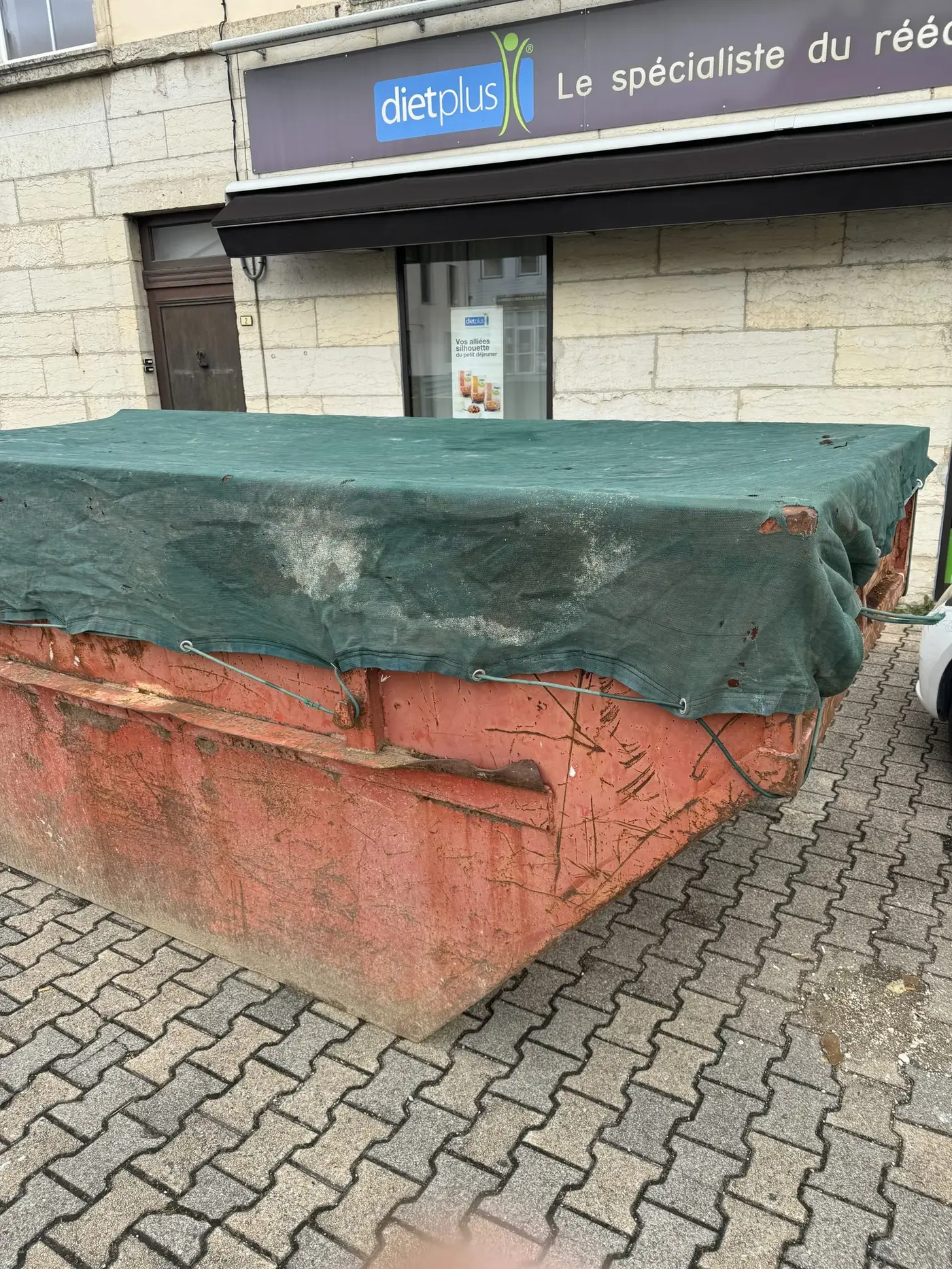 Benne bâchée posée sur un trottoir
