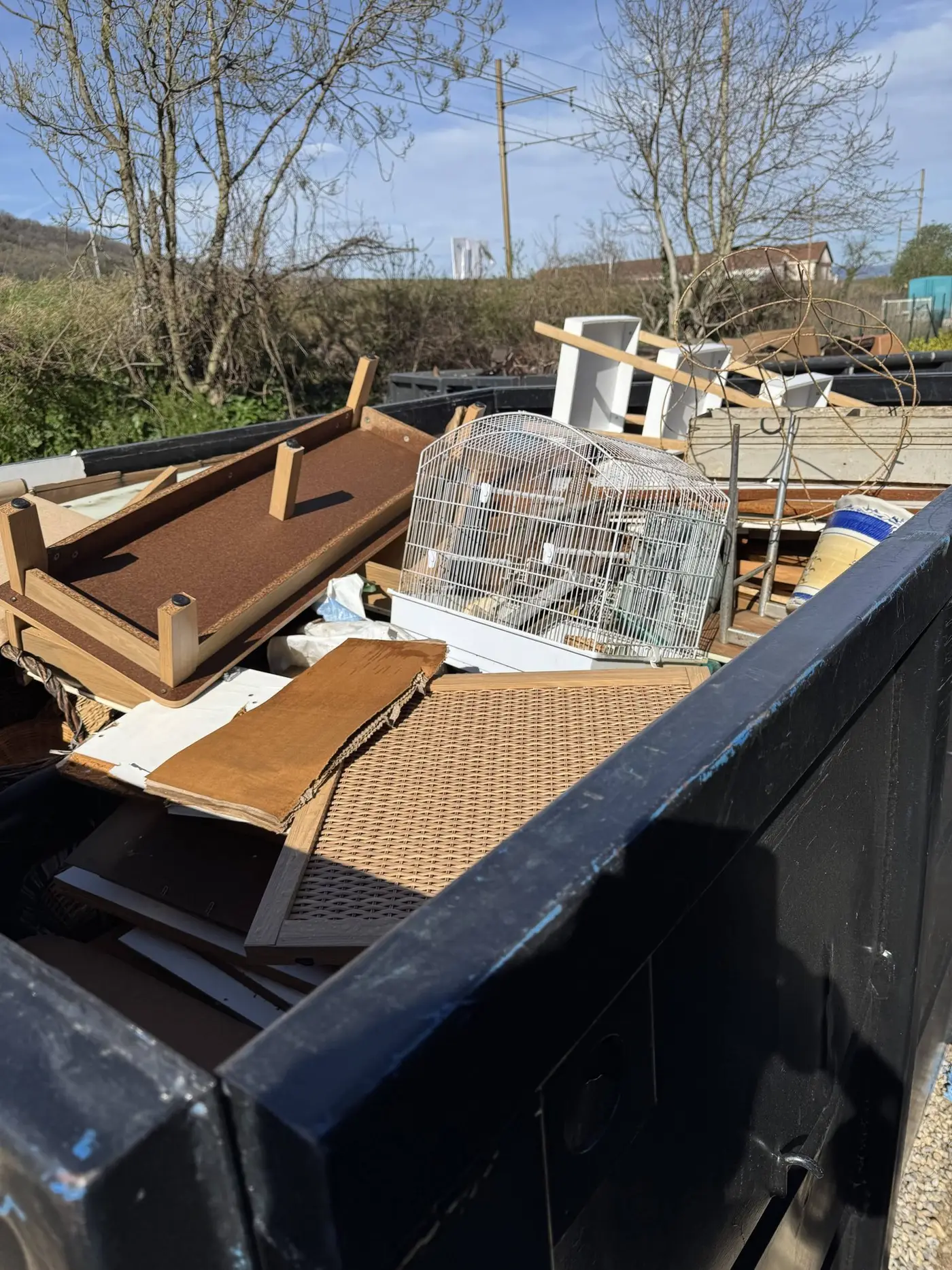 Benne remplie de meubles et de planches lors d'un débarras